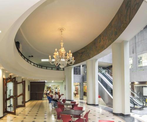 un gran vestíbulo con mesas, sillas y una lámpara de araña en Hotel Nutibara en Medellín