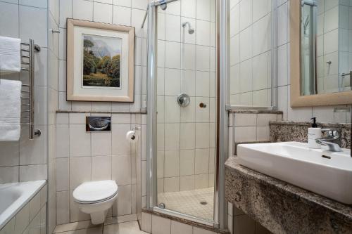 a bathroom with a toilet sink and a shower at Premier Hotel Quatermain in Johannesburg