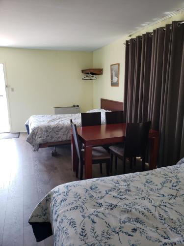 a hotel room with two beds and a table and chairs at Olympia Motel in Niagara Falls