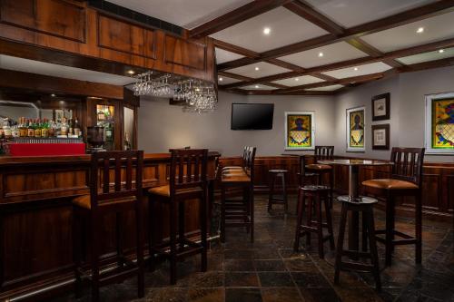 a bar with wooden bar stools and a tv at Premier Hotel Quatermain in Johannesburg