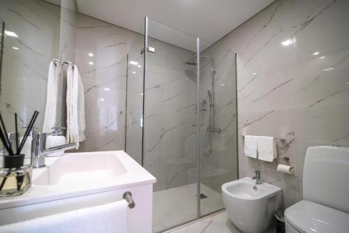a white bathroom with a sink and a shower at FERREIRA'S HOUSE Guimarães in Guimarães