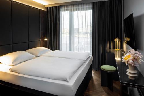 Un dormitorio con una gran cama blanca y una ventana en Hotel ROMY by AMANO en Berlín