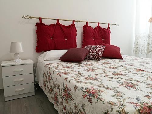 Un dormitorio con una cama con almohadas rojas. en A Casa di Santé, en Arnesano