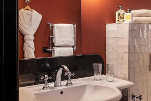 a bathroom with a sink and a mirror and towels at Grand Hôtel Chicago in Paris