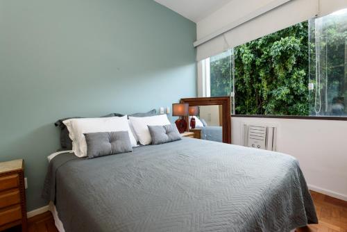 ein Schlafzimmer mit einem Bett und einem großen Fenster in der Unterkunft Sossego em Copacabana - Vista arborizada - BR1009 Z4 in Rio de Janeiro
