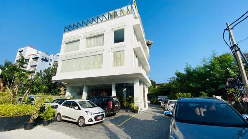 a white building with cars parked in a parking lot at The Terrace by Ladder Mgd by Citrine in Trivandrum