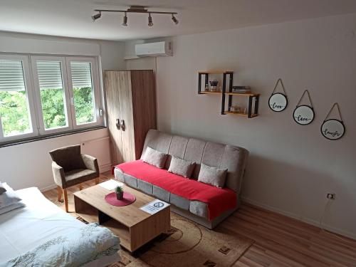 uma sala de estar com uma cama e um sofá vermelho em Apartman Banja Luka 2 em Banja Luka