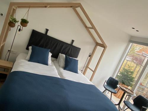 a bedroom with a large bed with blue pillows at B&B Bij tante Teun in Naaldwijk