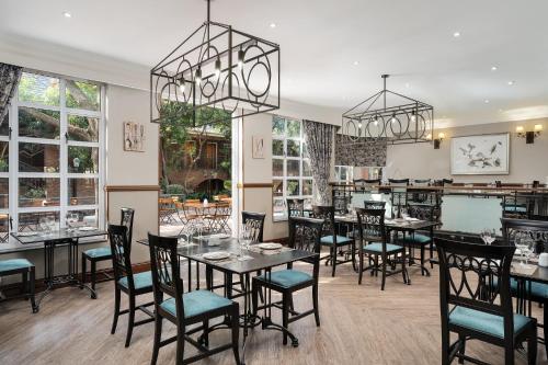 a dining room with tables and chairs and windows at Premier Hotel Quatermain in Johannesburg