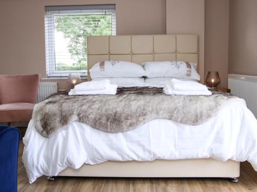 una camera da letto con un grande letto bianco con lenzuola e cuscini bianchi di Lindens Annexe a Shrewsbury