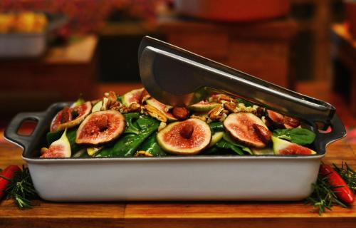 a pan filled with figs and greens with a spatula at Gandini Hotel in Itu