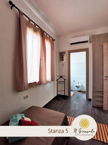 a bedroom with a bed and a bathroom with a window at IL GIRASOLE in Porto Torres
