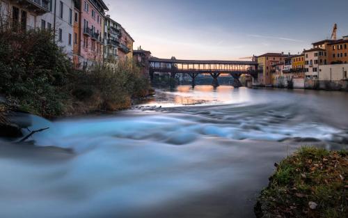 a river in a city with a bridge in the background at Al Vecchio Porto in Bassano del Grappa