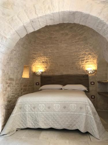 a stone walled room with a bed and a fire place at Tipico Resort in Alberobello