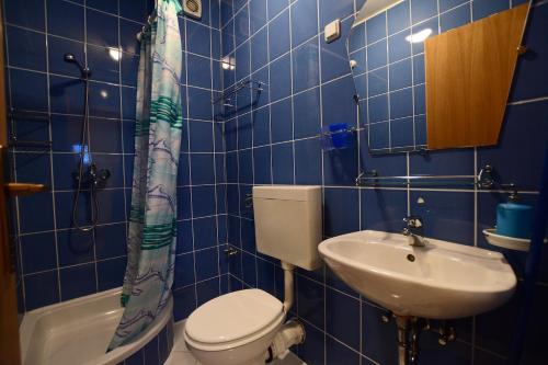 a blue tiled bathroom with a toilet and a sink at Apartmani HRGA in Vodice