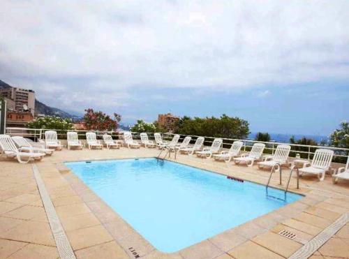 una piscina con tumbonas y un montón de plantas en Monaco à 300m du Casino - Grand Studio avec Piscine, en Beausoleil