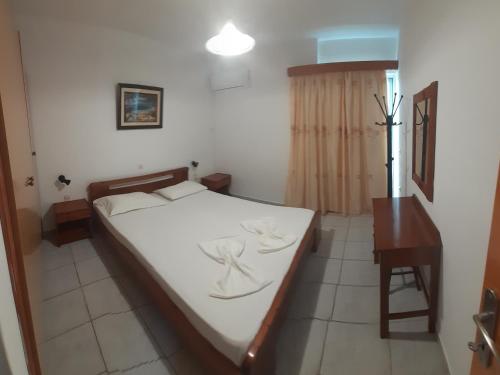 a bedroom with a bed with white sheets and a table at Zikas apartments in Marmari