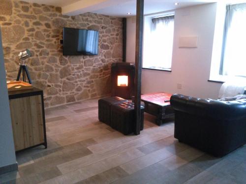 a living room with a couch and a tv on a stone wall at La estrella del viajero in Casas del Abad