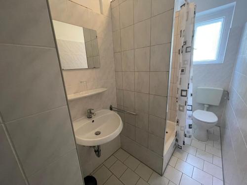 a white bathroom with a sink and a toilet at Pension Der Kretaner in Berlin
