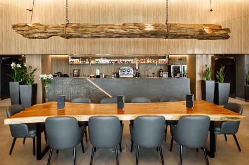 a large wooden table and chairs in a restaurant at Qosmo Brasov Hotel in Braşov