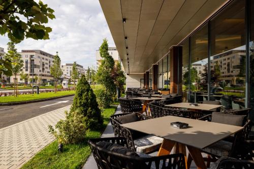 an outdoor restaurant with tables and chairs and a street at Qosmo Brasov Hotel in Braşov