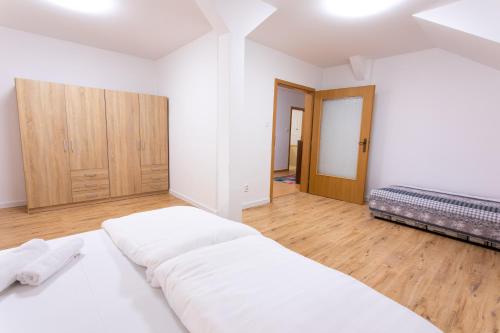 a white bedroom with a large bed and wooden floors at Hotel Novy Kastiel - Self check-in in Topoľčany