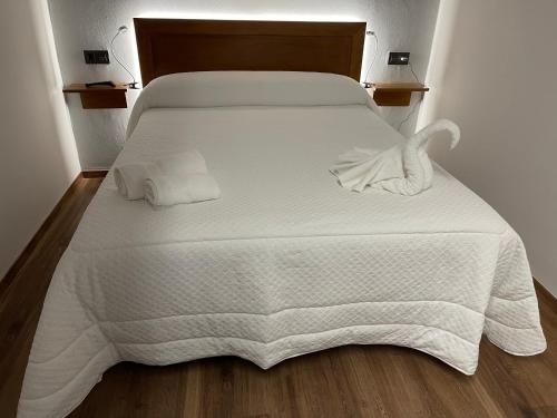 Una cama blanca con sábanas blancas y toallas. en La Era de Lario habitación con Jacuzzi, en Lario