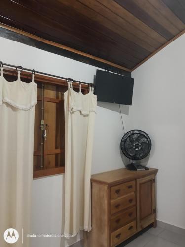 a room with a window with curtains and a dresser at Chalés do Apolinário in Tiradentes