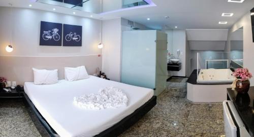 a bedroom with a large white bed and a bathroom at Motel Colorado (Adult Only) in Brasilia
