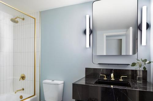 a bathroom with a sink, toilet and mirror at Kimpton Alton Hotel, an IHG Hotel in San Francisco
