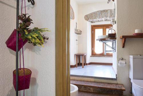 a bathroom with a toilet and a room with a window at Agriturismo Mulino Marghen - Restored WaterMill - Retreat Center in Zeri