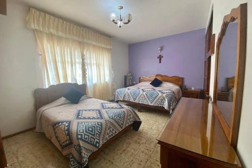 a bedroom with two beds and a cross on the wall at Casa Marquita en el centro de Talpa de Allende. in Talpa de Allende