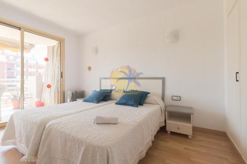 a white bedroom with a large bed with blue pillows at NOVELTY IBERPLAYA in Salou