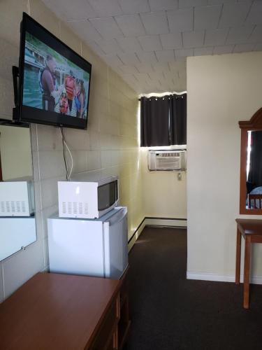 a room with a tv on the wall and a microwave at Olympia Motel in Niagara Falls