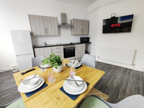 a kitchen with a wooden table with plates on it at Copper House- Smart Stay near Stadium & City in Swansea