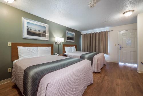 a hotel room with two beds and a door at HomeTowne Studios by Red Roof Orlando South in Orlando