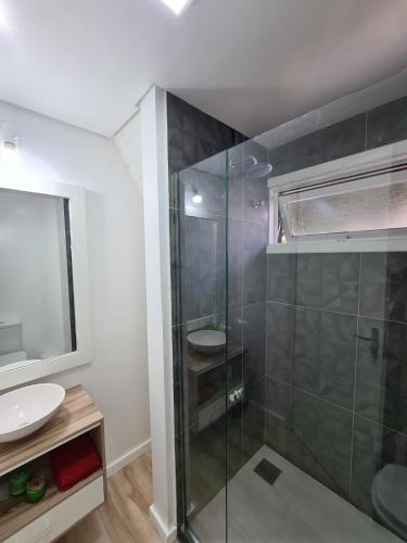 a bathroom with a glass shower and a sink at Chalé do Bosque in Gramado