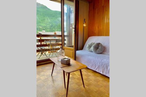 a bedroom with a bed and a table with a view at Spacieux T2 à 100m des pistes & WIFI ultra rapide in Saint-Chaffrey