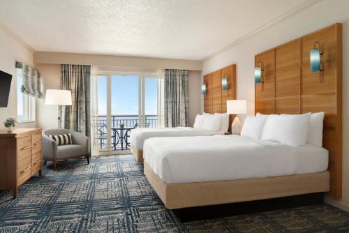 Holiday Inn & Suites Ocean City, an IHG Hotel في آوشين سيتي: غرفة فندقية بسريرين وبلكونة