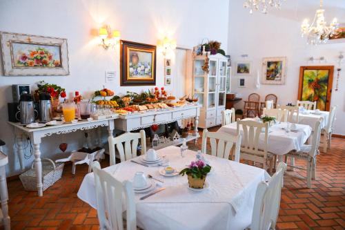 a restaurant with white tables and white chairs and food at Pousada Vale Dos Figos in Urussanga
