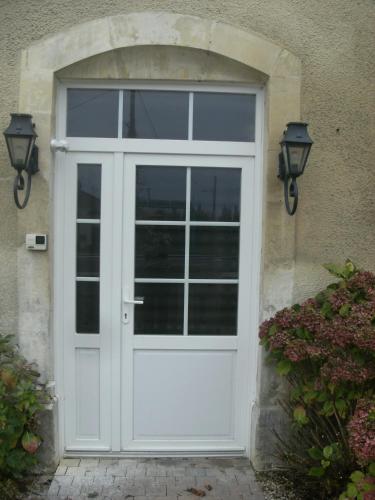 une porte blanche sur une maison avec deux lumières dans l'établissement jolie chambre dans ancien corps de ferme, à Bellengreville