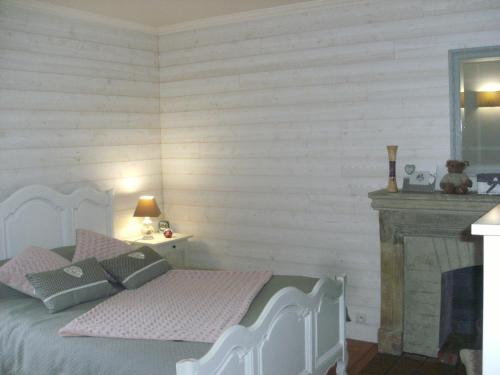 1 dormitorio con cama con almohadas rosas y chimenea en jolie chambre dans ancien corps de ferme, en Bellengreville