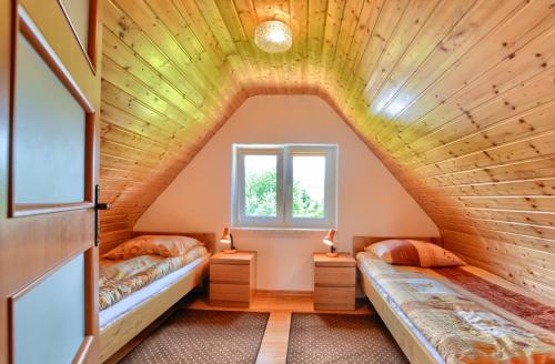 an attic bedroom with two beds and a window at Domki nad Stebnikiem in Ustrzyki Dolne