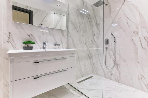 ein weißes Bad mit einem Waschbecken und einer Dusche in der Unterkunft Green Stone Apartments Hotel in Rafailovici