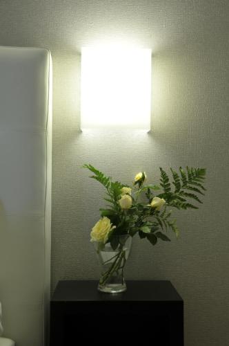 a vase of flowers on a table under a light at Gemini Suite in Rome