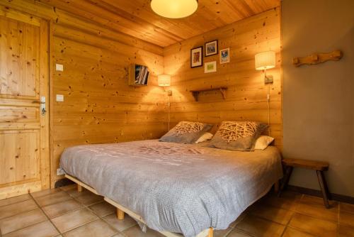 een slaapkamer met een bed in een houten kamer bij LES MURZIERS ** in Notre-Dame-de-Bellecombe