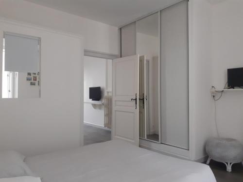 ein weißes Schlafzimmer mit einem Bett und einem Spiegel in der Unterkunft Appartement PAP2S in Millau