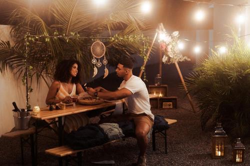 Ein Mann und eine Frau sitzen an einem Picknicktisch in der Unterkunft The Palm Leaf Apartments in Noord