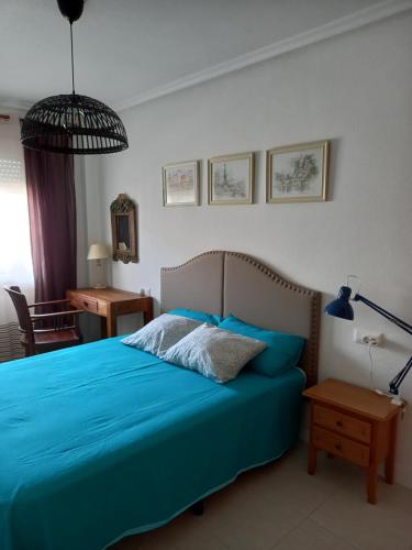 Schlafzimmer mit einem blauen Bett, einem Schreibtisch und einer Lampe in der Unterkunft Apartamento ROMERO Cabo Roig, solárium opcional in Orihuela
