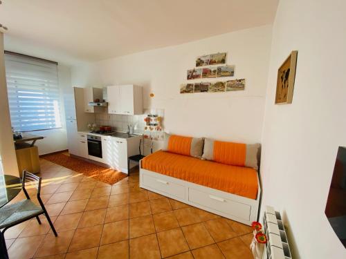 a living room with an orange couch and a kitchen at B&B Marilyn's House in Gragnano